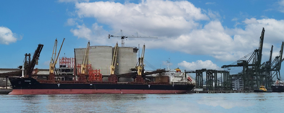 wide shot of port facility with silos against a bright blue sky