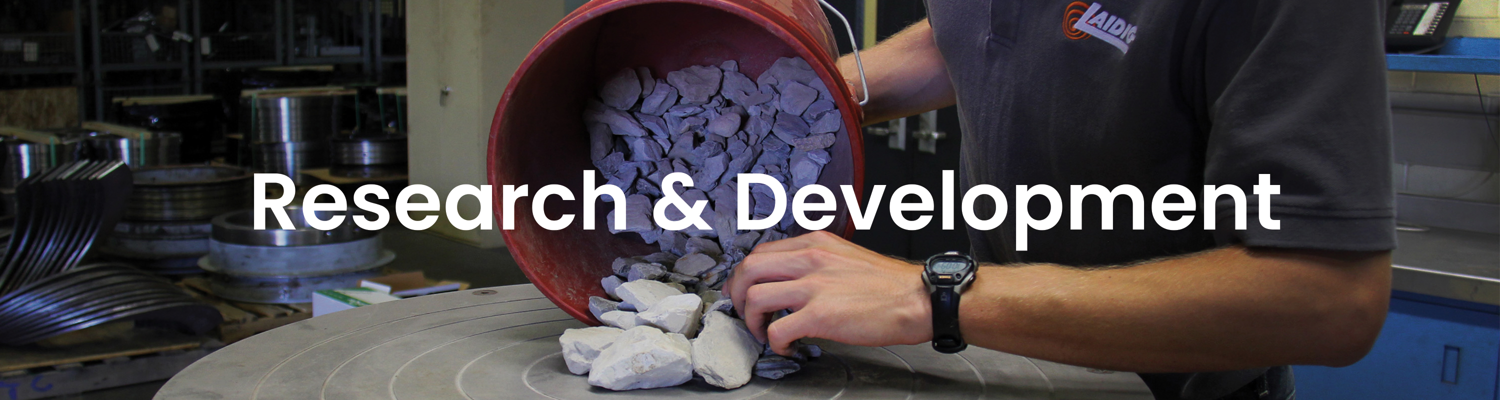 research lab background with white text that reads RESEARCH AND DEVELOPMENT bulk material handling system, bridging, rat-holing, material flow, reclaim, reclaimer, silo unloading, unloader, bulk material storage, reclaim system, dry bulk unloading, grain unloading